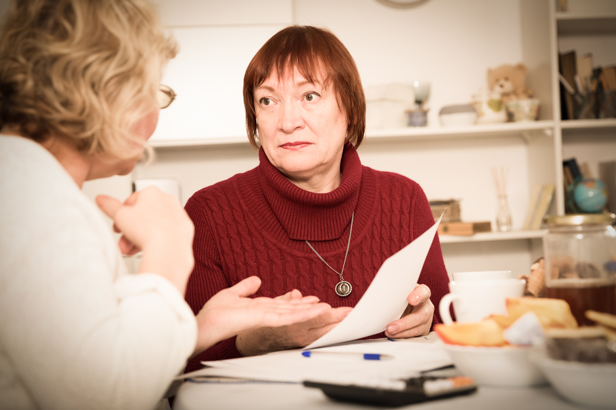 Frustrated senior lady having conversation with female about some documents